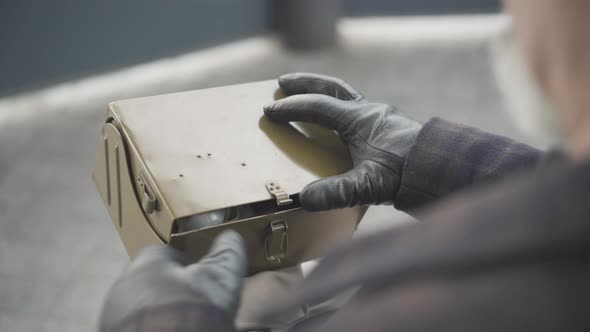 Unrecognizable Intelligence Agent or Spy Opening Box with Toxins in Spring or Autumn Park. Confident alt