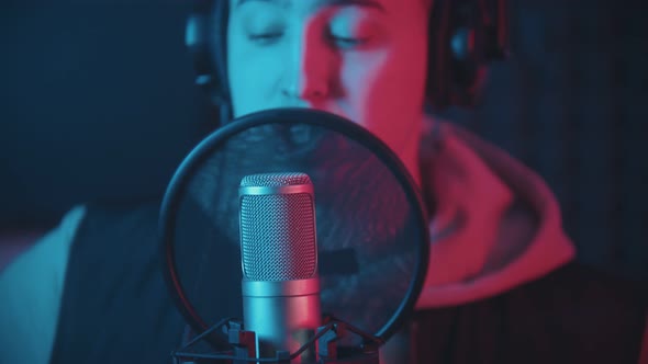 A Man in Hoodie Rapping Through the Pop-filter in the Microphone alt