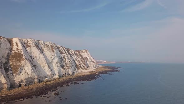 Drone flies low away from the White Cliffs of Dover with beautiful turquoise sea in the foreground. alt