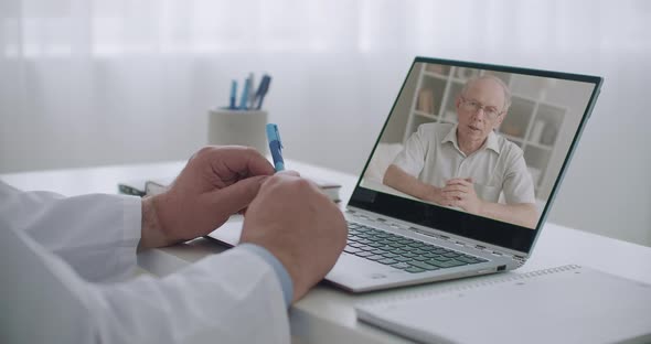 Elderly Man Is Consulting with Psychologist By Videochat, His Face on Screen of Laptop in Office of alt