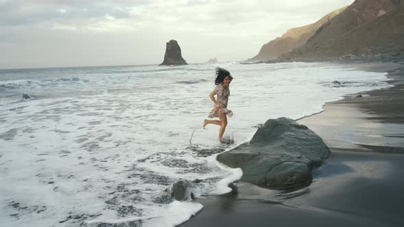 Young Woman in a Beautiful Dress Runs Along the Black Volcanic Black Sand Beach Benijo in the North alt