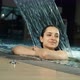 Happy Girl Smiling for Someone in Swimming Pool. Beautiful Woman Resting in Spa