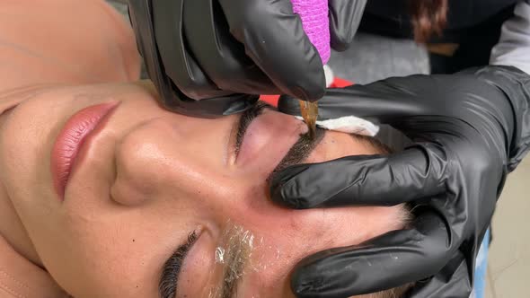 Master in Gloves Using Special Needle Stains the Eyebrows Using Hair Technique