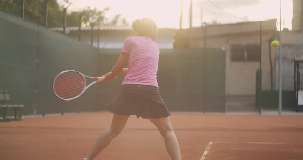 Young Woman Walking Through Tennis Court with Racket. Backside View of Attractive Brunette Female in alt