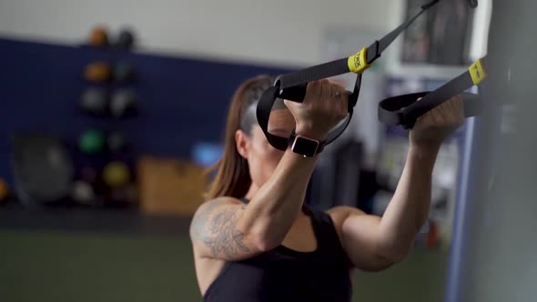 Athletic woman doing cable bicep work on cables in gym alt
