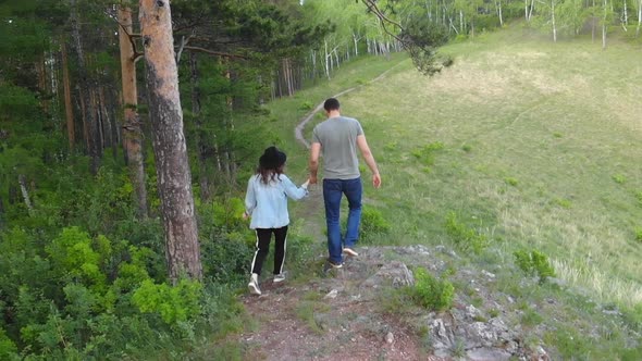 Aerial Shot Of A Pair Of Young People Walking Along A Forest Path By