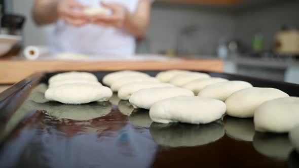 A Woman in the Kitchen Sculpts Pies and Puts Them on a Baking Sheet alt