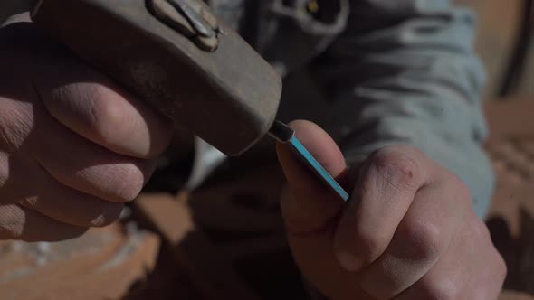 Craftsman hand working with stone. Sculpture with a sculpting tool and hammer carving stone.  alt