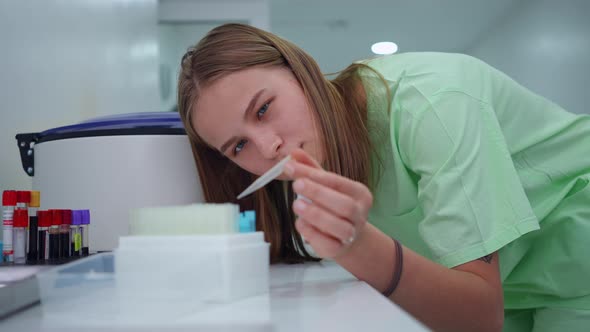 Concentrated Beautiful Young Woman Analyzing Test Tubes in Laboratory Thinking Standing at alt
