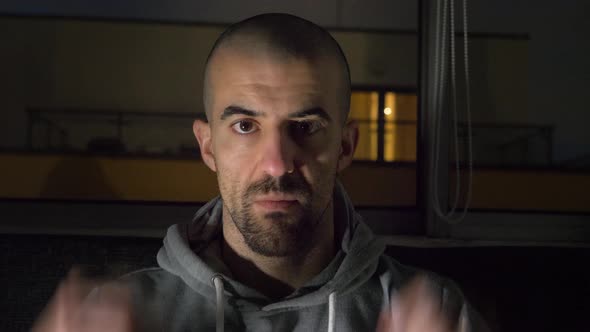 Man at home wearing a hoodie and staring at camera alt