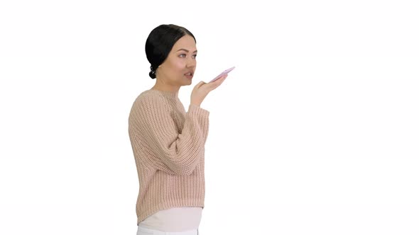 Young Woman Talking on the Phone Holding It To Her Face While Walking on White Background alt
