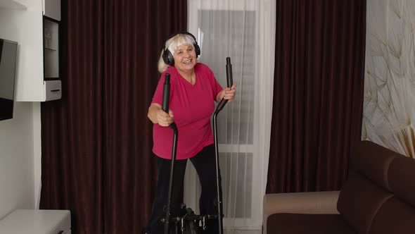 Senior Woman in Sportswear Using Orbitrek Listening Music at Home Doing Sport Cardio Exercises alt