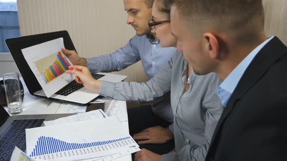Coworkers Examining Charts with Sales Result During Team Meeting in Office alt