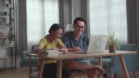 Happy Asian Father And His Daughter Looking At Laptop Computer alt