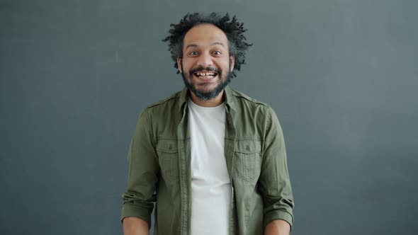 Portrait of Crazy Mixed Race Guy Clapping Hands and Looking at Camera with Funny Face alt