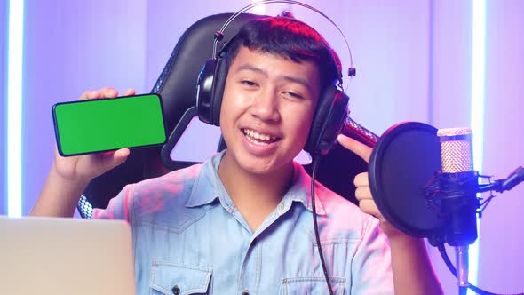 Asian Kid Boy Holding Mobile Phone With Mock Up Green Screen While Live Stream alt