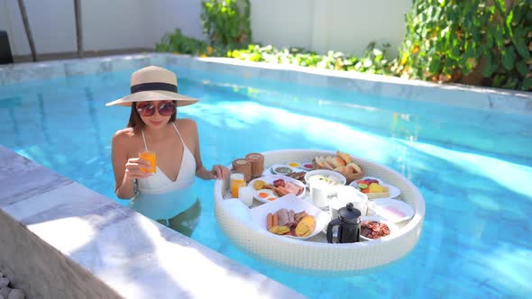 Woman with floating breakfast in pool alt