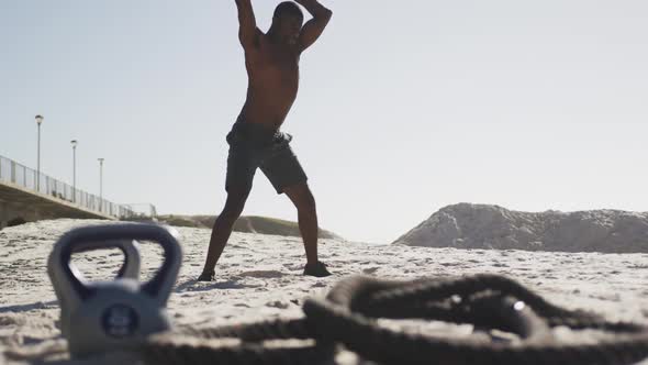 African american man working out with a medicine ball at the beach alt