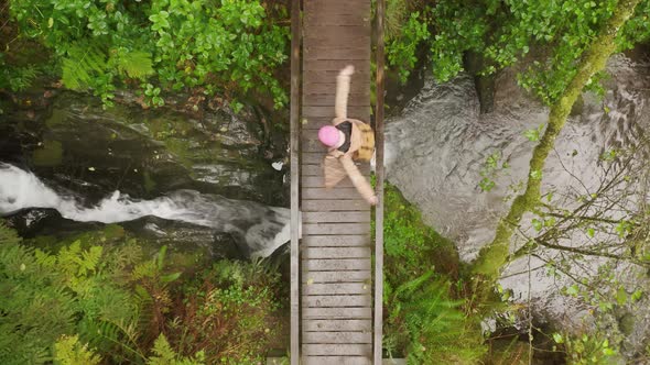 Cheerful Happy Joyful Young Woman Tourist on Wet Wooden Bridge Dancing in Rain alt