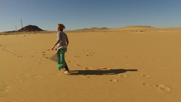 Happy woman running barefoot in desert, Egypt alt