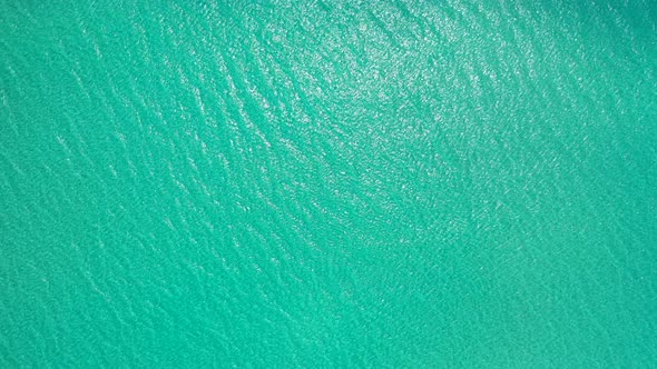 Turquoise texture of shallow lagoon near exotic beach with white clean sandy sea bottom, seen from h alt