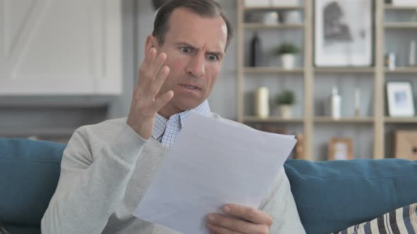 Middle Aged Man Feeling Upset while Reading Documents, Contract alt