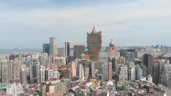 Panning and rotating aerial view of Macau skyline on cloudy day alt