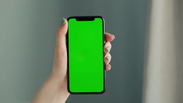 Woman hand using smart phone, touches the green screen. Green Mock-up alt
