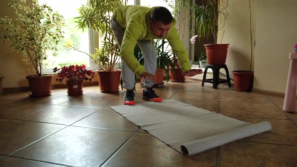 Young Man Rolling Up His Mat for Sport Training and Doing Pushups