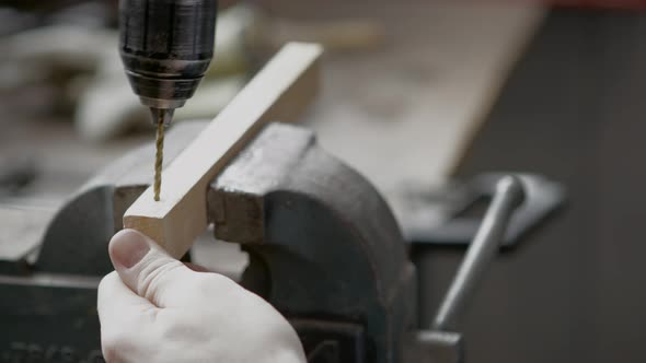 UHD An electric drill drills a small hole in a piece of wood held in a vice alt