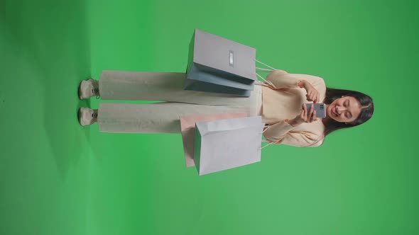 Full View Of Woman With Shopping Bags Enjoy Using Mobile Phone Shopping Online At Green Screen alt
