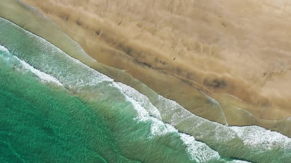 Aerial vertical View on the tropical sand Beach with Splashing Sea Waves