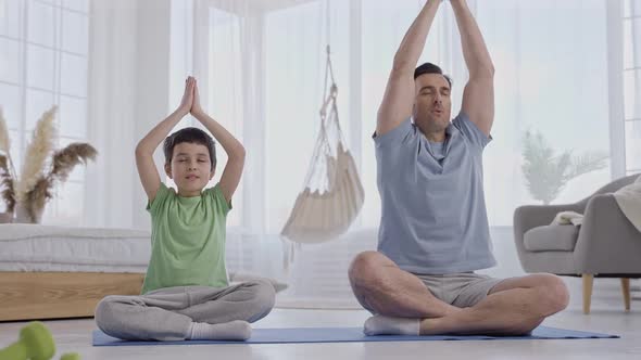 Father and Son Practicing Yoga in Living Room alt