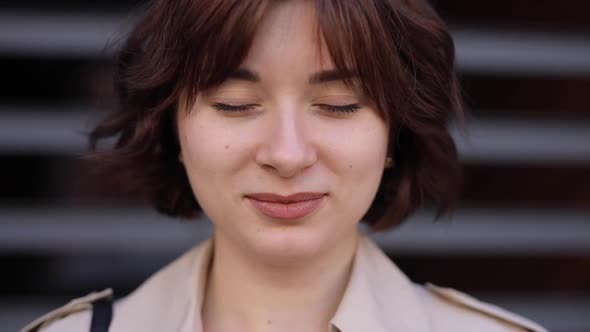 Woman in a Trench Coat Opens Her Eyes and Looks at the Camera