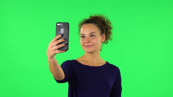 Portrait of Curly Woman Smiling Woman Texting on Her Phone . Green Screen alt