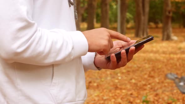 Man Using Smartphone In Autumn Park