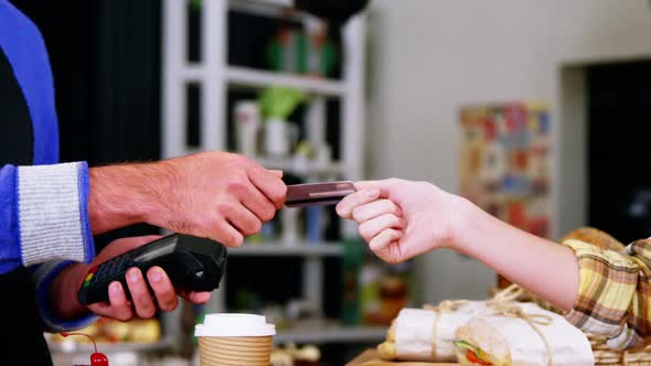 Customer making payment through payment terminal machine at counter alt