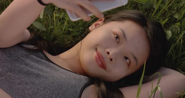 Young Asian Woman Lying on the Green Grass