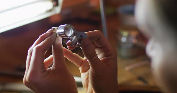 Close up of hands of caucasian female jeweller making jewelry in workshop alt