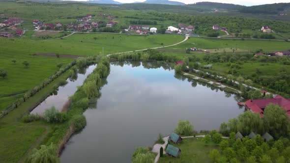 Drone shot flying over a beautiful reflective lake in the rural town of Sigmir in Transylvania Roman alt