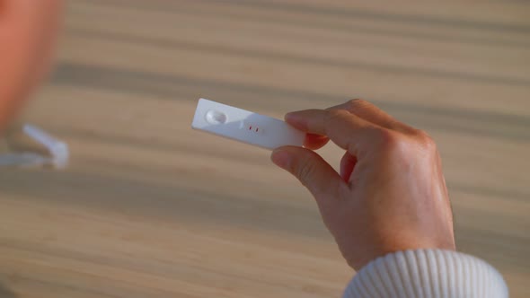 Close up shot of senior man hold antigen test kit with 2 stripe result. alt