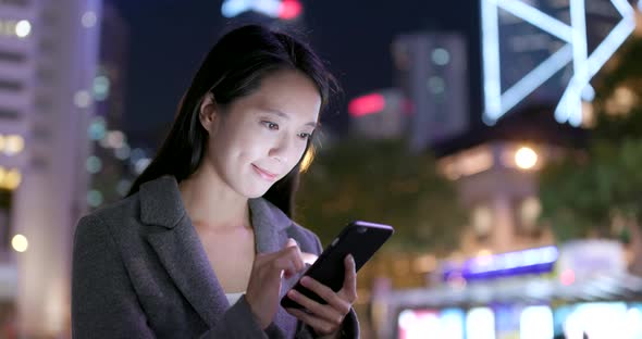 Businesswoman use of smart phone in city at night alt