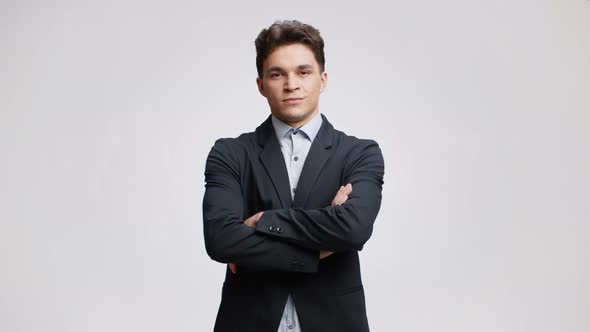 Studio Portrait of Young Confident Top Manager Wearing Formal Suit Posing to Camera with Folded Arms alt