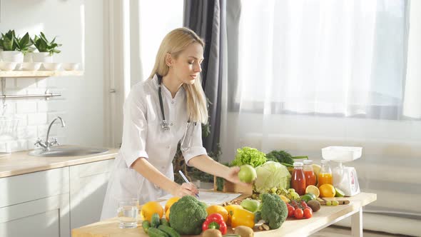 Nutritionistblogger in a White Coat Talks About Healthy Eating Standing at a Table with a Lot of