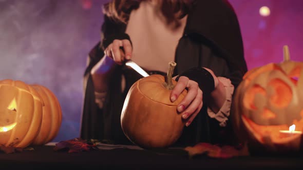 A witch carves a pumpkin for halloween. Beautiful lighting. Halloween! 4K.  Best  stock video.