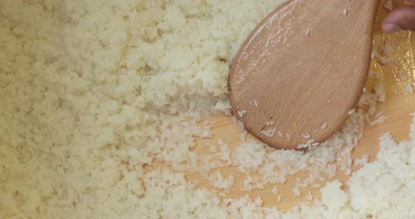 Chef Mixing Japanese White Rice Using Wooden Spoon For Sushi Dish In The Kitchen. - high angle shot alt