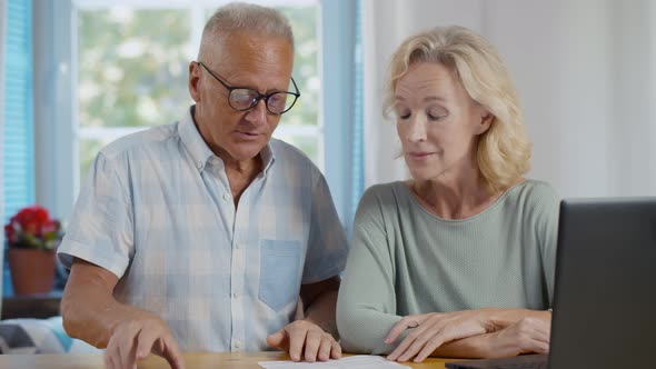 Senior Couple at Home Discuss Income and Pay Bills Online Scanning Qr-code alt