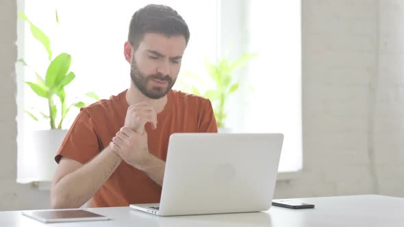 Young Man Having Wrist Pain While Using Laptop in Office alt
