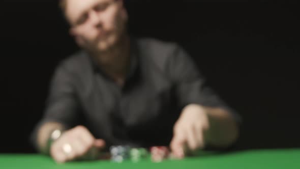 Man on Black Background Doing Call with Red Chips on the Green Poker Table alt