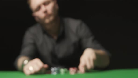 Man on Black Background Doing Call with Red Chips on the Green Poker Table